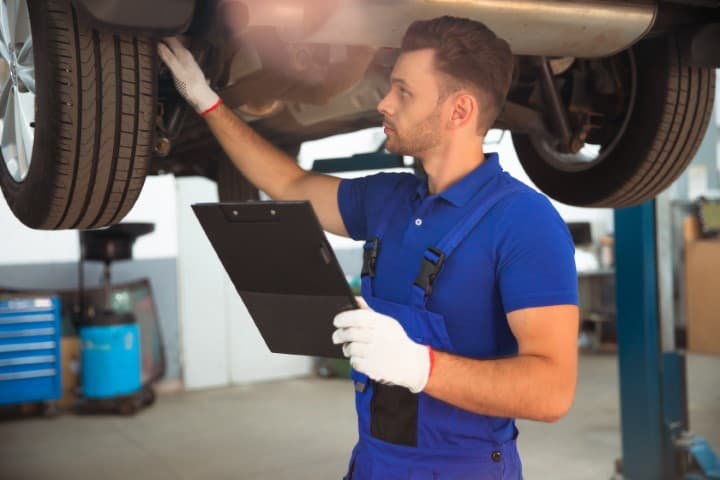Confident and concentrated young and experienced car repair specialist with a tablet in his hand inspects and diagnosis the car for breakdowns
